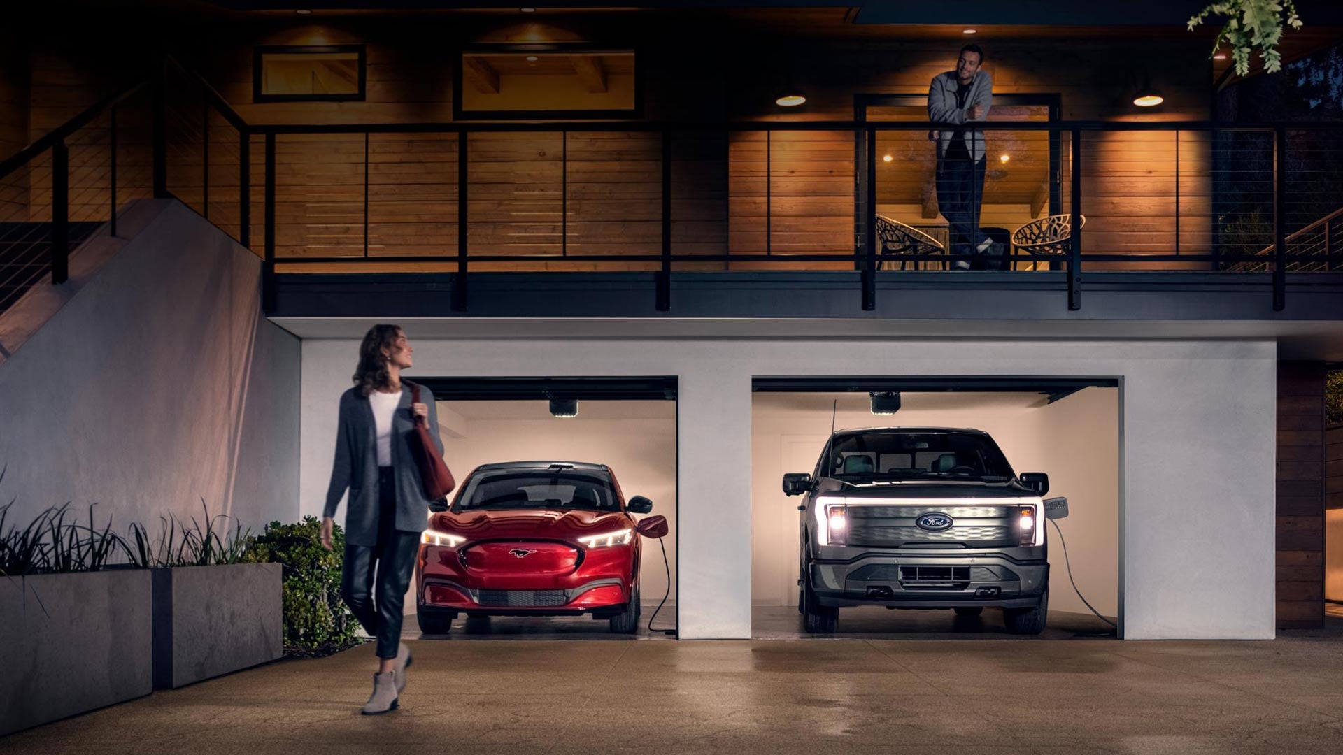 Woman walking out from home garage with a 2024 Mustang® Mach-E and Ford Lightning® truck in plugged-in and charging | Courtesy Ford Conyers in Conyers GA